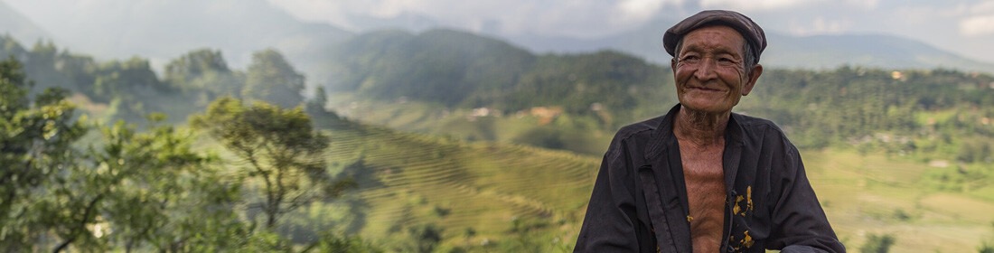 Landmand i Sapa-dalen med rismarker i baggrunden, som du besøger på rejser til Vietnam