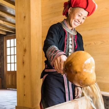 Red Dao woman preparing herbal bath at Topas Riverside lodge in Nam Cang