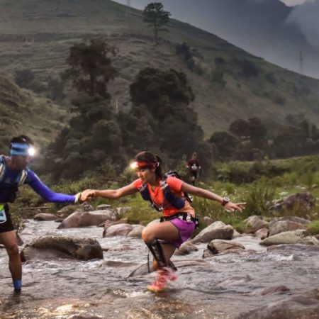 Trailøbere hjælper hinanden med at krydse flod i Vietnam Mountain Marathon
