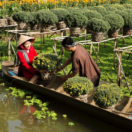 Mand og kvinde i båd ved blomsterplantage i Mekong